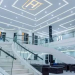 Luxurious modern interior with curved staircase and glass railings, symbolizing Ham Group’s growth.